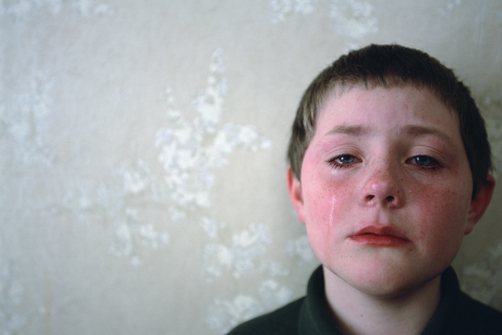 A young boy's tear streaked face is red from crying.